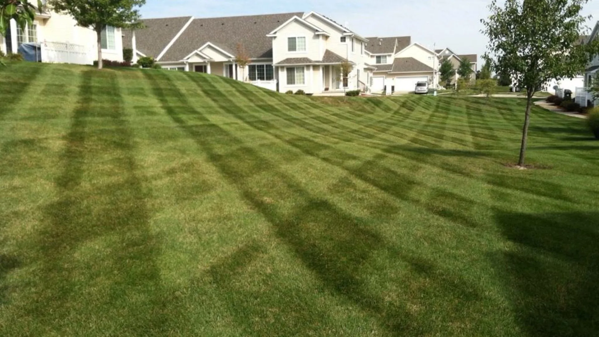 Hillside lawn with mowing patterns in Urbandale, IA.