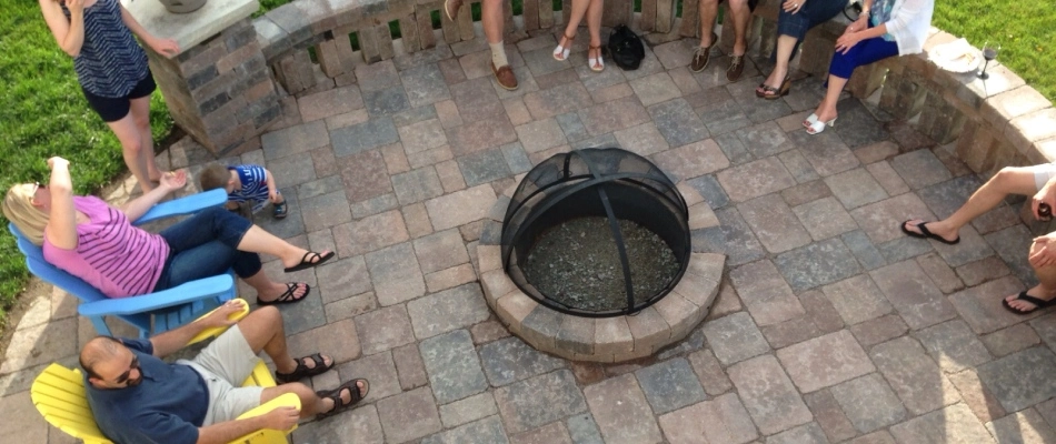 Friends gathered around custom built stone fire pit for patio area in Ankeny, IA.