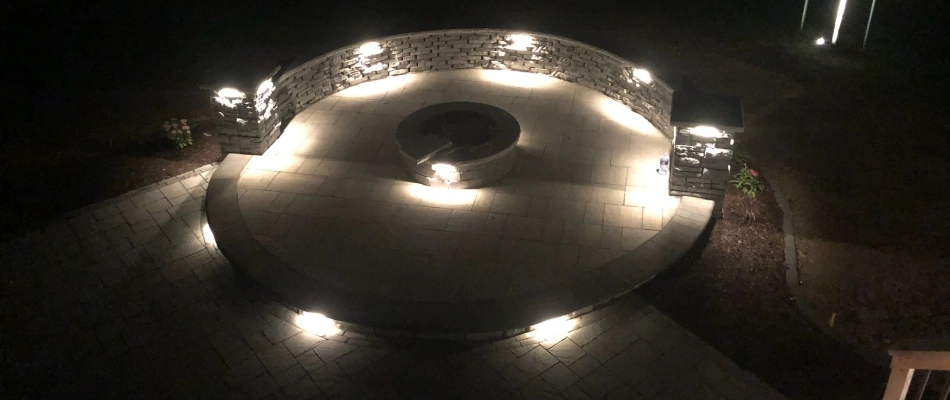 Seating wall around fire pit area with lighting installed in Urbandale, IA.
