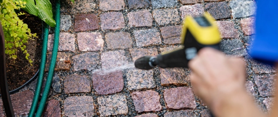 Professionals spraying dirty pavers in Urbandale, IA.