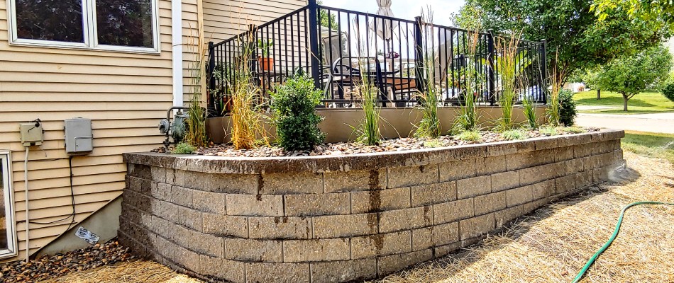 Retaining wall installed beside fenced patio in Grimes, IA.