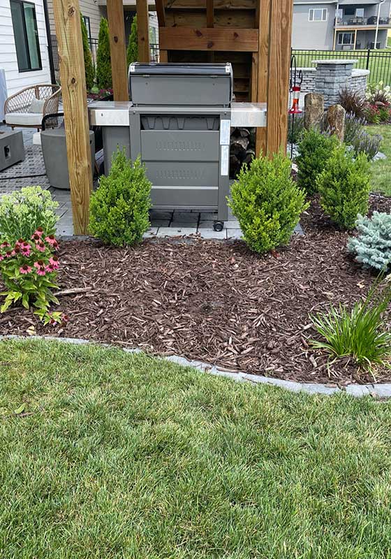 Landscape bed with mulch and small shrubs and flowers near Waukee, IA.